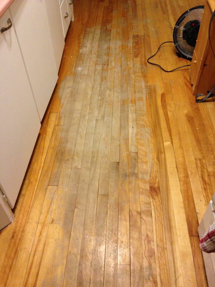 A picture of a hardwood floor with a worn out finish due to regular water. This can be refinished by our Moncton wood floor refinishing experts!